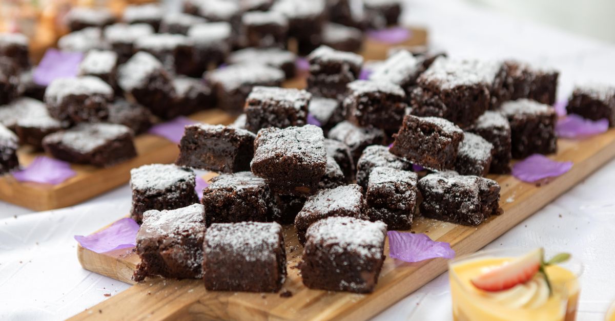 Close-up of chocolate brownies dusted with icing sugar on a wooden board. Perfect dessert setting.